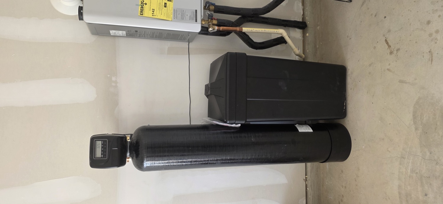 Whole-home water softener with brine tank and tankless water heater installed in a garage